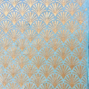 Pode incluir: Um fundo azul com um padrão repetitivo de formas de leque douradas.