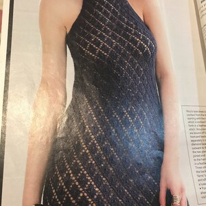 May include: A navy blue, halter-style lace dress with a high neckline. The dress features a diamond-patterned openwork design. The dress is sleeveless and has a fitted bodice that flows into a flared skirt.