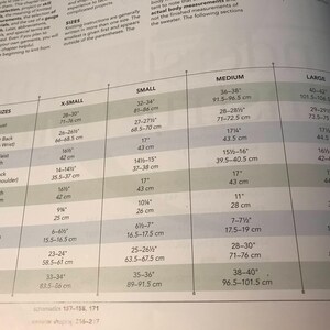 May include: A page from a knitting pattern book displaying a size chart for women's sweaters. Measurements are listed in inches and centimeters for bust, waist, hips, and other areas, with sizes ranging from X-Small to Large.
