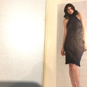 May include: A navy blue, halter-neck dress with a diamond-patterned knit design. The dress is knee-length and worn with dark blue heels. The image is from a magazine, with the number 58 visible.