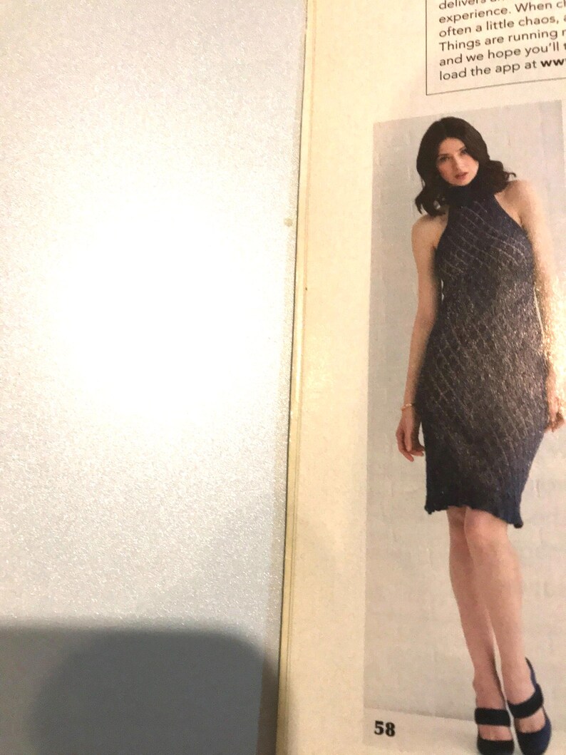 May include: A navy blue, halter-neck dress with a diamond-patterned knit design. The dress is knee-length and worn with dark blue heels. The image is from a magazine, with the number 58 visible.