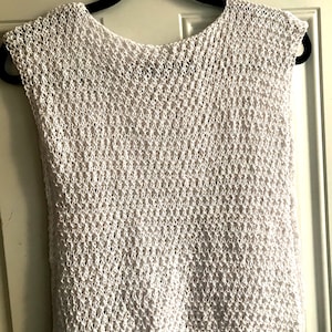 Peut inclure: Top sans manches en crochet blanc avec un col rond. Le haut est fait d'un tissu délicat et ajouré.