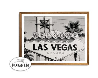 May include: Black and white photograph of the iconic "Welcome to Fabulous Las Vegas" sign with a starburst above it. The sign is in a diamond shape with the words "Las Vegas" in bold letters and "Nevada" below. The sign is framed in a wooden frame.