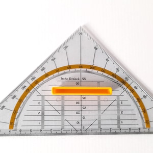 Puede incluir: Un transportador de plástico transparente con un deslizador amarillo y marcas en grados. El transportador está etiquetado como "Techn Dreieck SS 06".