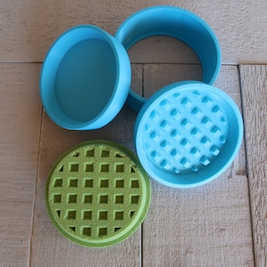 May include: A three-piece grinder set with a light blue lid, a light blue base with a diamond-shaped pattern, and a green base with a waffle-like pattern.