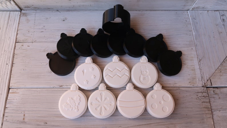 K&ouml;nnte beinhalten: Ein Set mit 10 wei&szlig;en Weihnachtsbaumschmuck-Ausstechern aus Kunststoff mit verschiedenen Designs, darunter Schneeflocken, Stechpalme, ein Schneemann und ein Zickzackmuster. Das Set enth&auml;lt au&szlig;erdem 8 schwarze Ausstecher aus Kunststoff in der gleichen Ornamentform.