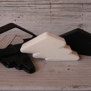 May include: Two black cloud-shaped cookie cutters and one white cloud-shaped cookie cutter. The cutters are made of plastic and are stacked on top of each other.