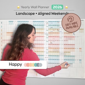 Peut inclure: Un grand planificateur mural annuel 2026 avec une mise en page en grille, avec le texte "Yearly Wall Planner 2026" et "Landscape • Aligned Weekends." Le planificateur est effaçable à sec. Une personne écrit sur le planificateur avec un marqueur.