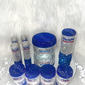 以下が含まれることがあります： ラインストーンが付いた青と銀の容器7個セット。容器には「アクアフRESH」の文字が書かれており、赤、白、青のデザインになっています。