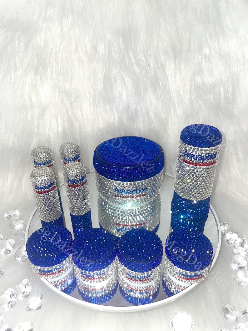 以下が含まれることがあります： ラインストーンが付いた青と銀の容器7個セット。容器には「アクアフRESH」の文字が書かれており、赤、白、青のデザインになっています。