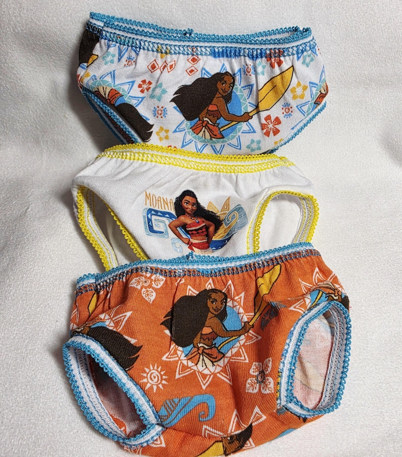May include: Three pairs of children's underwear featuring a cartoon character. The top pair is white with blue trim, the middle pair is white with yellow trim, and the bottom pair is orange with blue trim. Each pair has a different design of the same character.