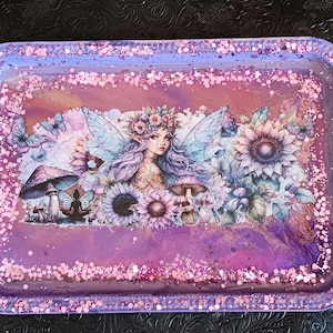 May include: A purple resin tray with a fairy and floral design. The tray has a glittery finish and is perfect for holding jewelry or other small items.