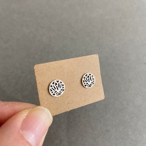 May include: A pair of silver stud earrings with a delicate, intricate lotus flower design.