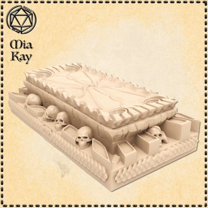 May include: A beige, rectangular box with a detailed, ornate design. The box is decorated with skulls and rope-like accents. The top of the box is open, revealing a detailed interior.