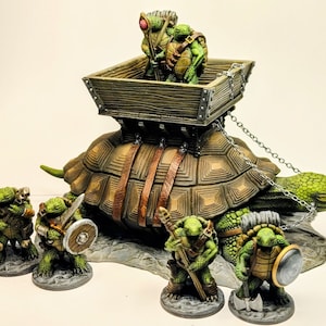 May include: A group of five green turtle figurines, some carrying weapons, riding on a large turtle with a wooden cart on its back. The cart is attached to the turtle with a silver chain.
