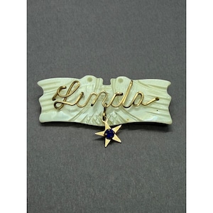 Broche vintage de nácar con alambre dorado y nombre escrito en forma de estrella, estilo MCM.