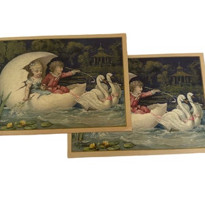 Peut inclure: Deux enfants dans une grande coquille d'œuf blanche sont tirés par trois cygnes blancs sur un lac. Les enfants portent des vêtements rouges et bleus. Le lac est entouré d'arbres et d'un kiosque en arrière-plan.