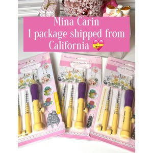 May include: A collection of punch needle sets, each with a yellow and purple handle. The packaging is pink and white, with floral designs. The text "Mina Carin" and "Punch Needle Set" are visible.