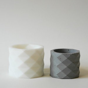 May include: Two concrete planters with a geometric diamond pattern. One planter is white and the other is gray.