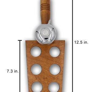 May include: A wooden wine bottle holder with a silver bell and a wooden handle. The holder has six circular openings and measures 12.5 inches tall, 5.1 inches wide, and 3.9 inches deep. The wooden base is 7.3 inches tall.