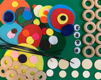 May include: Assortment of felt circles in various colors and sizes, including red, blue, yellow, green, and black. There are also wooden rings and googly eyes.