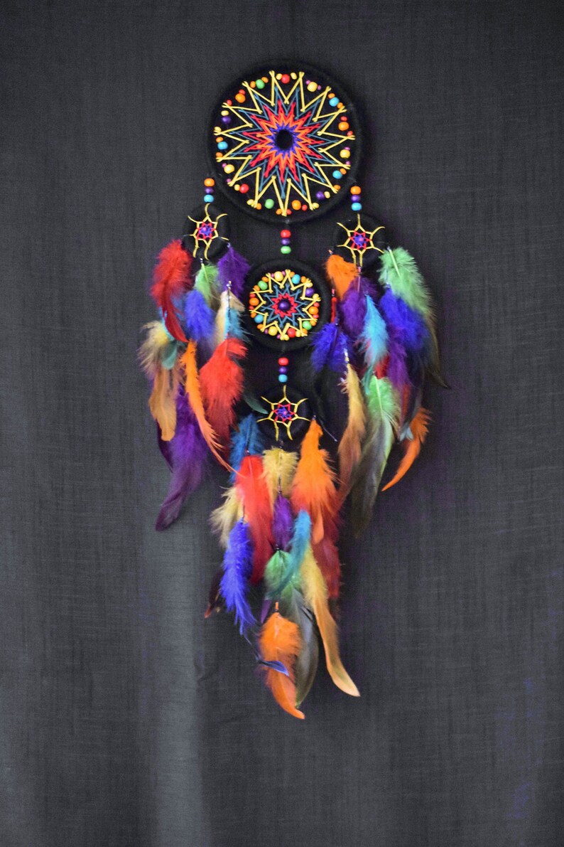 May include: A colorful dreamcatcher with three black hoops decorated with beads and colorful feathers. The hoops are embroidered with a starburst pattern.