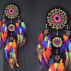 May include: Two colorful dreamcatchers with black felt circles and colorful feathers. The dreamcatchers have a starburst design in the center of each circle.