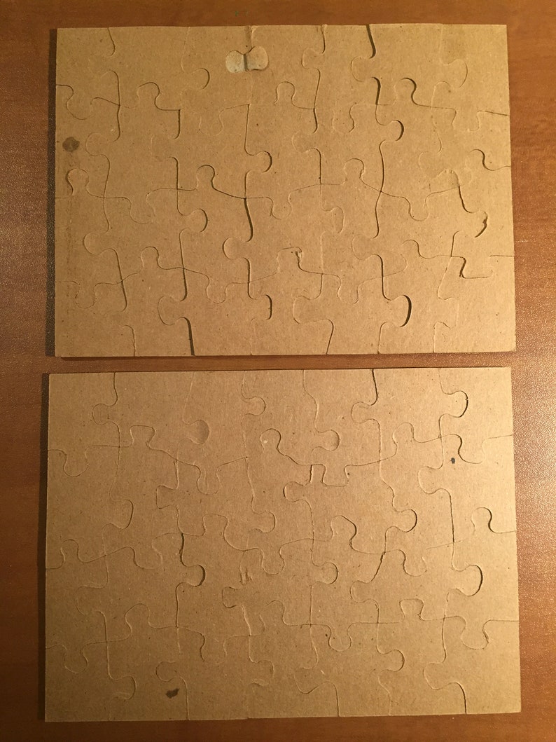May include: Two brown cardboard puzzle pieces with a jigsaw pattern. The pieces are blank and ready to be used for a custom puzzle.