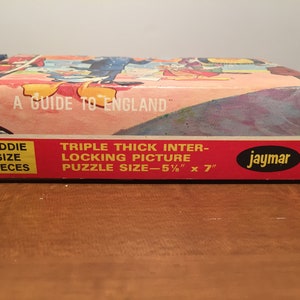 May include: A red and white cardboard box for a "A Guide to England" jigsaw puzzle. The box features a picture of a cartoon scene with a red and white striped background. The box is labeled "Triple Thick Inter-Locking Picture" and "Kiddie Size Pieces". The puzzle size is 5 1/2 inches by 7 inches. The box is labeled "Jaymar" and has the number 8741 printed on it.