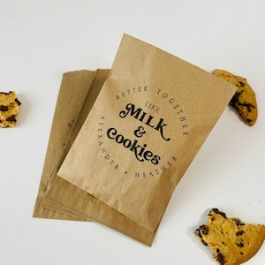 May include: Four brown paper bags with the text "Better Together Like Milk & Cookies Alexander + Heather" printed on the front.