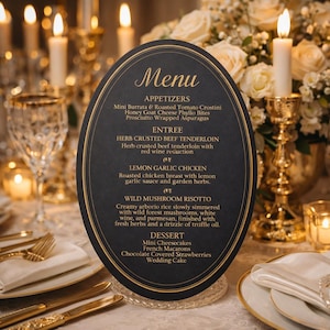 May include: An oval-shaped black menu card with gold trim, displaying a wedding menu. The menu lists appetizers, entrees, and desserts. The card is set on a clear, decorative stand, surrounded by candles and floral arrangements.