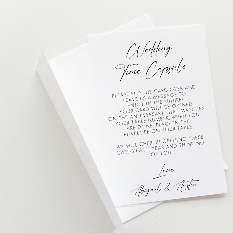 Puede incluir: Tarjeta blanca con texto negro que dice "Wedding Time Capsule". La tarjeta instruye a los invitados a escribir un mensaje para la pareja para abrir en su aniversario. La tarjeta est&aacute; firmada "Love, Abigail & Austen".