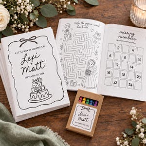 May include: A white activity book titled A Little Book of Wedding Fun with Lexi + Matt and September 24, 2026 printed on the cover, featuring a wedding cake illustration, a maze, and a missing numbers game, alongside a small box of crayons.