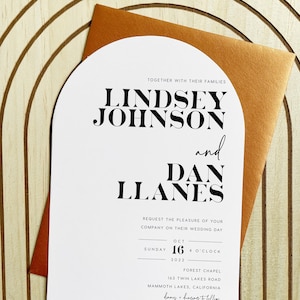 May include: A white wedding invitation with a modern arch design. The invitation features the names Lindsey Johnson and Dan Llanes in bold black text. The wedding date is October 16, 2022, at 4 o'clock at the Forest Chapel, 163 Twin Lakes Road, Mammoth Lakes, California.