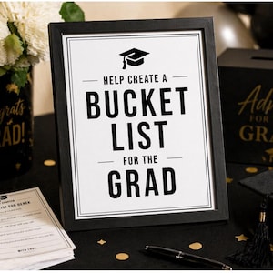 May include: A framed sign with the text "HELP CREATE A BUCKET LIST FOR THE GRAD" in black. The sign is part of a graduation party setup, with a "Congrats GRAD!" vase and an "Advice for the Grad" box.
