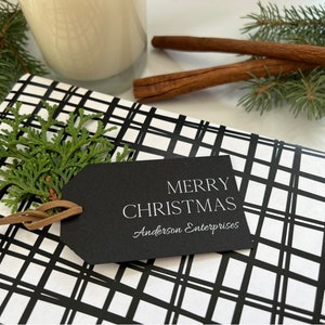May include: A black and white plaid gift wrap with a black gift tag that says "Merry Christmas Anderson Enterprises".