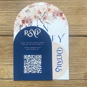 May include: A blue RSVP card with a floral design and a QR code. The text on the card reads "RSVP" and "SCAN THE QR CODE TO RSVP ONLINE ON OUR WEBSITE. KINDLY RESPOND BY SEPTEMBER 1ST".