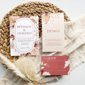 May include: A set of three wedding invitations with a boho theme. The invitations are printed on cream and blush colored cardstock with a floral design and the text "Bethany & Lincoln" and "Details". The RSVP card is red with a floral design and the text "Kindly RSVP".