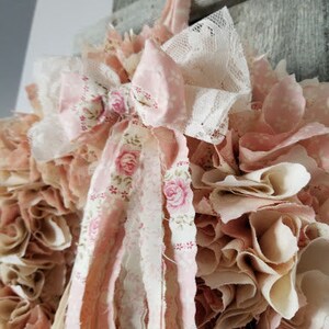 Puede incluir: Una corona de tela rosa y blanca con un gran lazo rosa y detalles de encaje. La corona est&aacute; hecha de tiras de tela que se juntan y se fruncen para crear un aspecto completo y esponjoso.