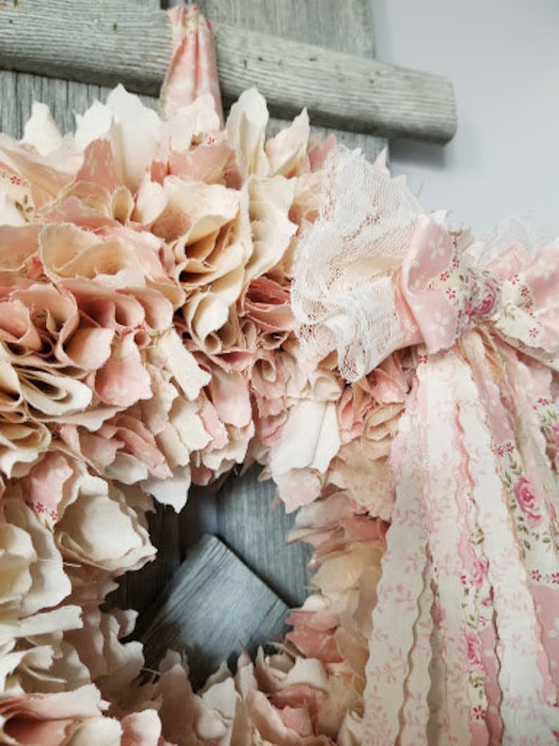 Puede incluir: Una corona de tela rosa y blanca con detalles de encaje y cinta. La corona est&aacute; hecha de recortes de tela y est&aacute; decorada con encaje y cinta rosa y blanca.