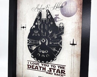 May include: A framed print with a vintage background featuring a black silhouette of the Millennium Falcon spaceship from Star Wars. The text "I love you to the Death Star and back" is printed in red below the spaceship. The text "Episode V 7.27.2019" is printed in red below the text.