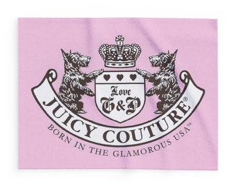 Può includere: Un'etichetta rettangolare rosa con il logo "Juicy Couture". Il logo include una corona, due cani terrier e le parole "Love G&P" all'interno di uno scudo. È presente anche il testo "Born in the Glamorous USA".