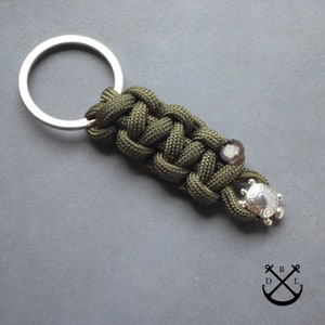 May include: A green paracord keychain with a silver key ring and a silver turtle charm.