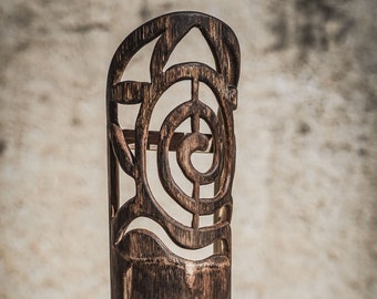 May include: A dark brown wooden lamp with a carved design featuring a spiral and geometric shapes. The lamp has a black cord.