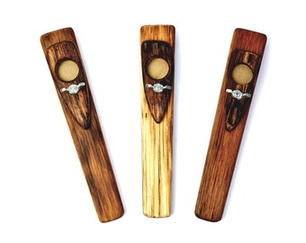 May include: Three wooden ocarinas, each with a different wood grain pattern. The ocarinas are brown and have a silver metal ring around the mouthpiece.