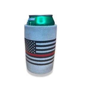 May include: White can cooler with a black and white American flag design and a red stripe across the middle. The cooler is holding a green can.