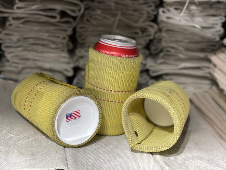 Puede incluir: Tres enfriadores de latas amarillos hechos de material tejido. Uno contiene una lata roja y blanca, otro tiene una tapa blanca con una peque&ntilde;a pegatina de la bandera estadounidense. Los enfriadores tienen costuras rojas y un lazo.