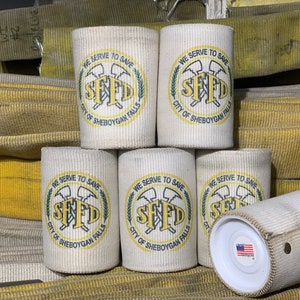 May include: Six white canvas can coolers with a yellow and green logo that reads "We Serve To Save SFFD City of Sheboygan Falls".