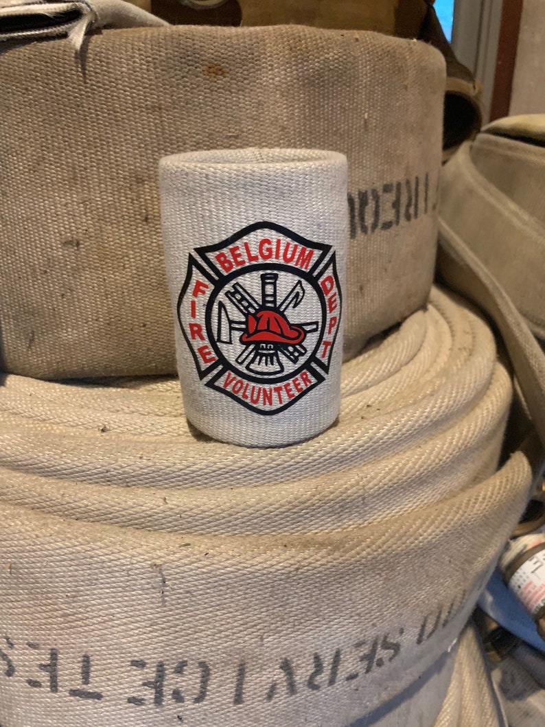 May include: White can cooler with a black and red fire department logo. The logo says "Belgium Fire Dept Volunteer".