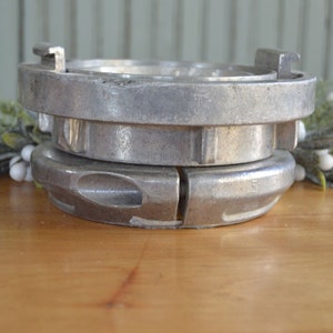 May include: Two silver metal fire hose couplings stacked on top of each other. The top coupling has a small handle on the side. The bottom coupling has a number "5" on the side.